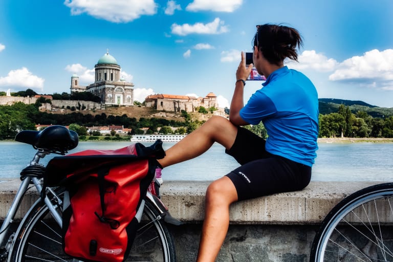 Ciclista in sosta che scatta una foto al Parlamento di Budapest lungo la Ciclabile del Danubio, Ungheria viaggi in bici 